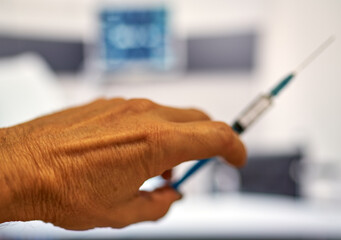 a fragment of a hand holds a syringe for vaccinations