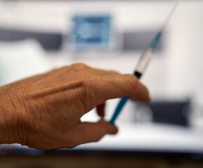 a fragment of a hand holds a syringe for vaccinations