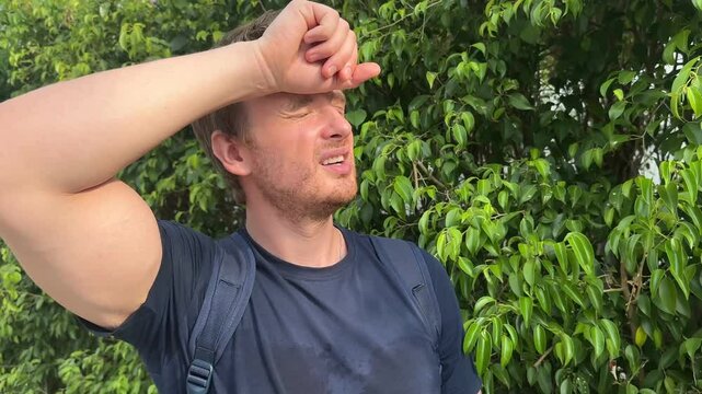 Young man suffering from heat, high temperature, hot weather. Dangerous sun, sunstroke