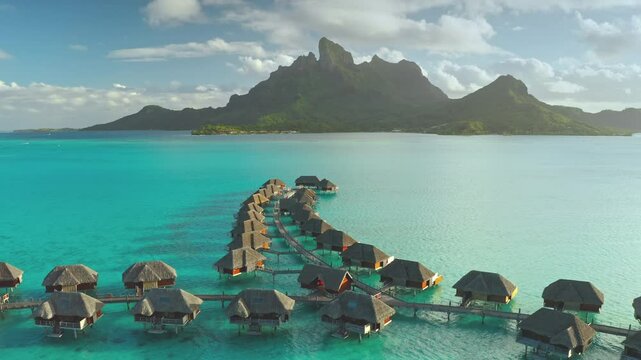 Luxury villas overwater bungalows hotel resort in turquoise water lagoon of Bora Bora tropical island. Mount otemanu in sunset. Remote wild nature paradise, exotic vacation summer travel. Aerial view