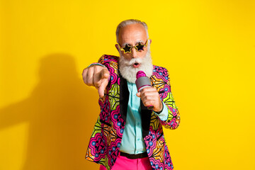 Portrait of classy eccentric man hold microphone point finger you wear vibrant blazer isolated on yellow color background