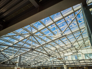 Fototapeta premium A large, open space with a clear roof and a blue sky. The roof is made of metal and has a lot of windows