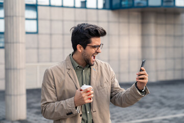 Energetic Businessman Reacts to Smartphone News with Coffee