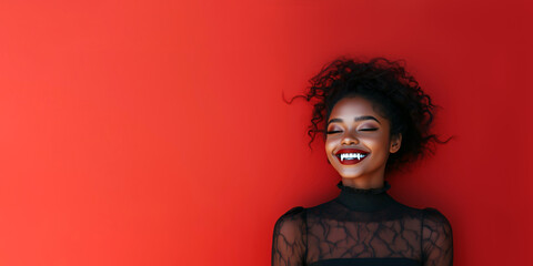 Fototapeta premium Black woman vampire. A smiling african woman with vampire fangs on a red background with copy space for text. For party invitation, Halloween poster