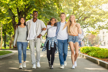 Obraz premium Carefree multiracial students walking together by public park after university