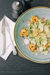 Top View of Fresh Salad with Cutlery and Pepper Shaker on a Wooden Table