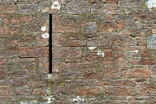 Red brown sandstone block and mortar building stone wall texture  background with arrow slit