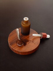 Minimalist composition with dropper bottle and coffee on a spoon. Skincare product concept. Front view. Dark background.