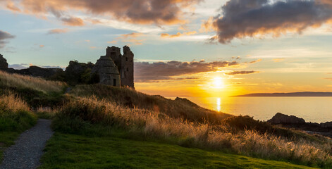 Golden sunset at Dunure Castle with dovecot, Firth of Clyde, Isle of Arran in background