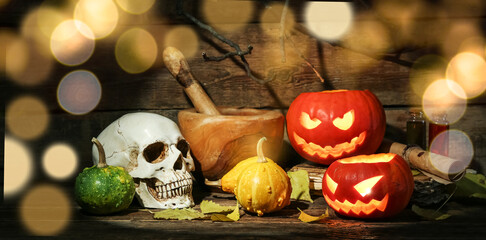 Halloween composition with jack-o-lanterns, pumpkins and skull on wooden table
