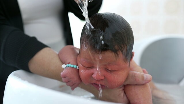 Newborn baby being lovingly cradled in a bath, with a hand gently resting on the baby's head for comfort and reassurance. baby's peaceful expression