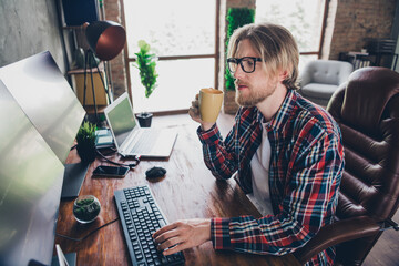 Photo of young senior level it specialist programmer man blond hair wearing eyeglasses and checkered shirt sitting workplace drinking coffee