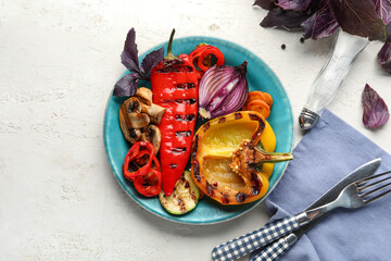 Plate with grilled vegetables and basil on white table