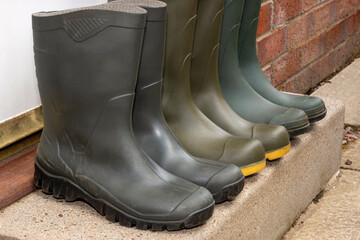 3 pairs mid and full height green rubber outdoor gardening wellington boots lined up in row on...