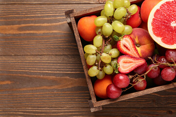Box with different fresh fruits on wooden background