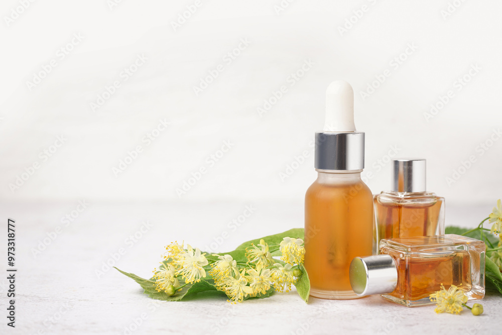 Wall mural bottles of essential oil and fresh linden flowers on light background