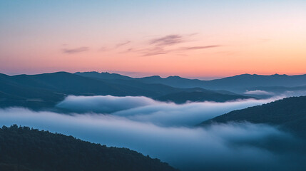 Early morning mist envelops the mountains as the sun rises over the landscape at dawn