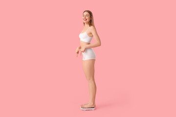 Young woman measuring weight on pink background. Diet concept