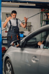 Serviceman navigates woman parking a car into mechanic workshop.
