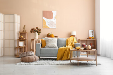 Interior of cozy living room with autumn decor, sofa and table