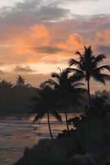 Obraz premium A silhouette of palm trees at a tropical sunrise or sunset. The sky is painted with shades of orange, pink and purple.