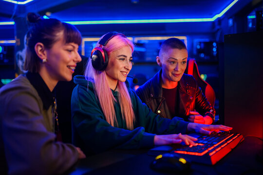 Gamer girl playing mmo game in cybercafe while her friends watching.