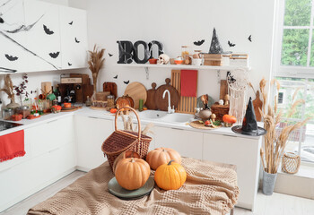 Interior of light kitchen decorated for Halloween with white counters and table