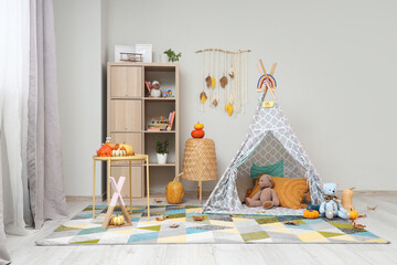 Interior of children's room with play tent, shelf unit and pumpkins