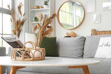 Interior of cozy living room with grey sofa, coffee table and vase of pampas grass, closeup