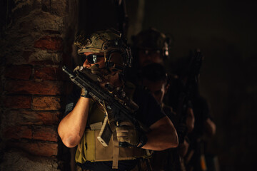 Air soft players hiding in dark ruined building and preparing for action