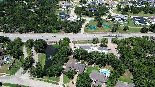 Water fountain small pond in lakeside residential neighborhood along West Southlake Boulevard, Keller, Texas, luxury mansion houses swimming pools in suburbs Dallas Fort Worth metroplex, flyover