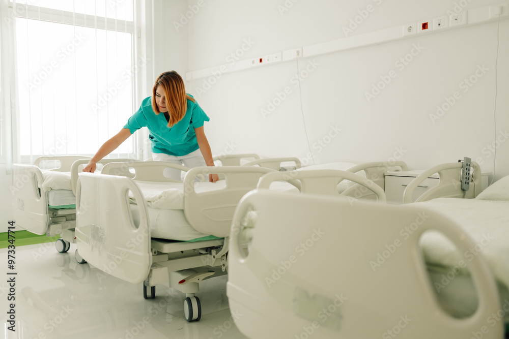 Wall mural nurse straightening up hospital bed in clean, modern patient room