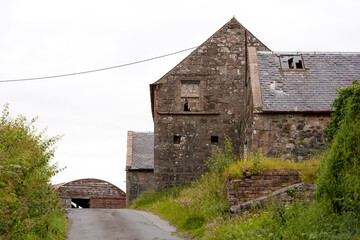 Abandoned ruin dilapidated sandstone, brick, corrugated iron and slate tile roof farm buildings...