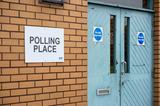 Democracy Election Voting Polling Place white sign on wall beside door entrance to polling station community centre