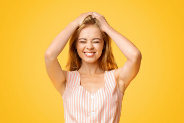 Fototapeta premium Pure Joy. Funny Teen Girl Grimacing And Touching Her Hair Over Yellow Background, Closeup