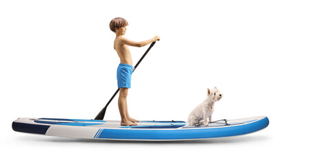 Full length profile shot of a boy paddling a SUP board with his dog