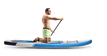 Full length profile shot of a man paddling a SUP board on knees