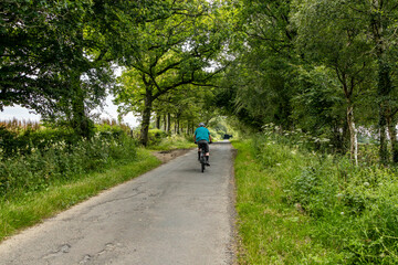 Obraz premium Healthy lifestyle: Senior retired man cycling along single track country road