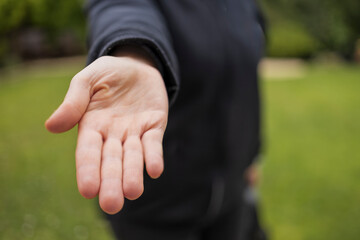 Demanding give that concept: Young caucasian woman holding flat hand out to viewer with palm up with blurry background