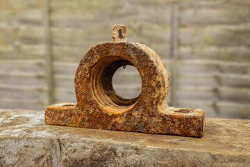 Discarded Industrial Relic: Rusty cast iron farm machinery shaft bearing housing on wooden block
