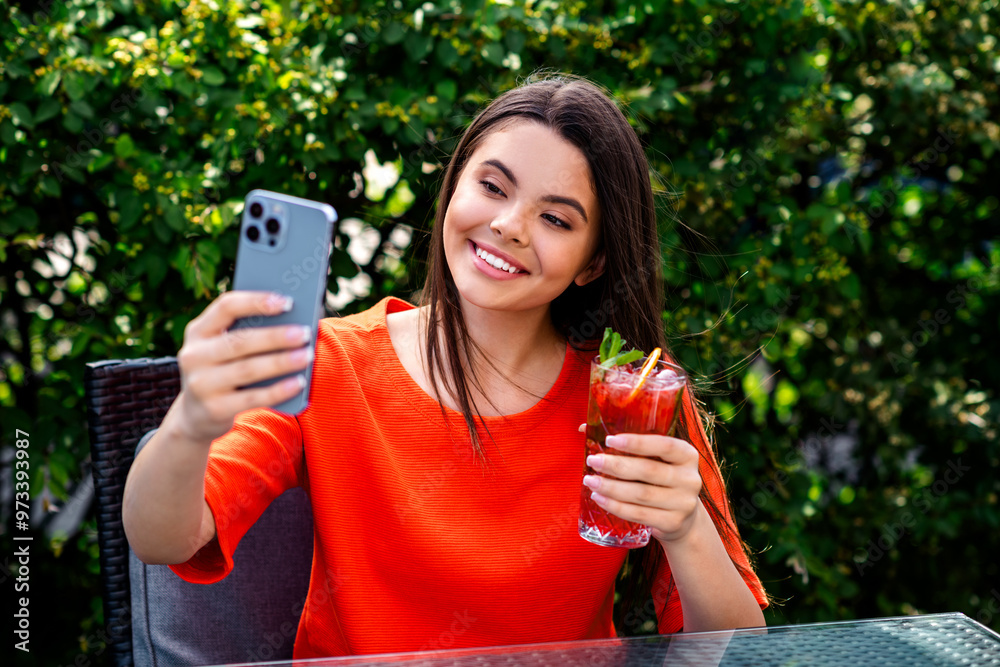 Poster Photo of attractive teen cheerful girl sit cafe table selfie photo cocktail wear red garment having fun outside outdoors