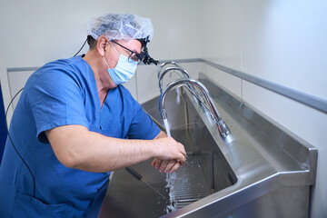 Doctor in mask cleaning hands before surgery