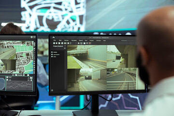 Middle eastern man locating delivery truck drivers in traffic and following the car direction via satellite map and CCTV radar footage. Agency employee works with gps tracking for shipment.