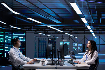 Teamworking technicians in data center call center responsible for providing logistics support to startups. Colleagues in server farm overseeing equipment systems and communicating with engineers