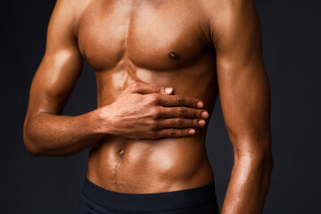 Fototapeta premium Bodybuilding Concept. Strong athletic afro man with muscular naked torso touching his body over black studio wall