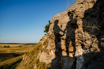 A dark silhouette of a person is distinctly cast upon a rugged, rocky cliff, creating a striking...