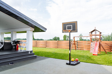 This modern backyard features a basketball hoop and a colorful playset, making it the ideal space for enjoyable family activities together © Aleksey
