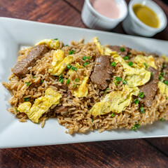 chaufa rice with chunks of meat, accompanied by homemade creams.