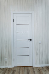 A room with a crafted wooden floor and a white door