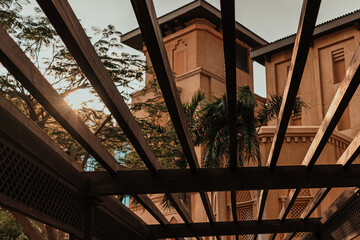 Obraz premium Sunlight shining through wooden pergola near traditional Arabic architecture 